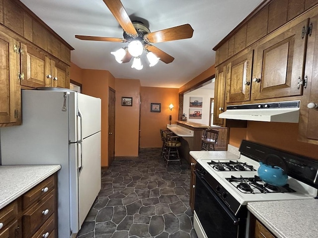 kitchen with freestanding refrigerator, under cabinet range hood, gas stove, and light countertops