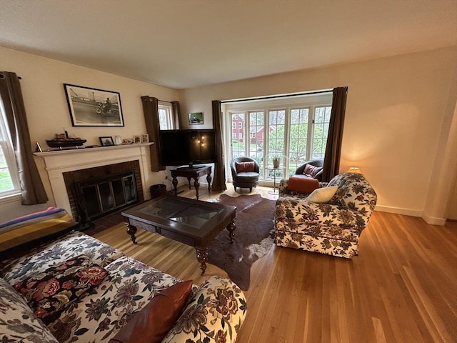 living room with baseboards, a fireplace with flush hearth, and wood finished floors