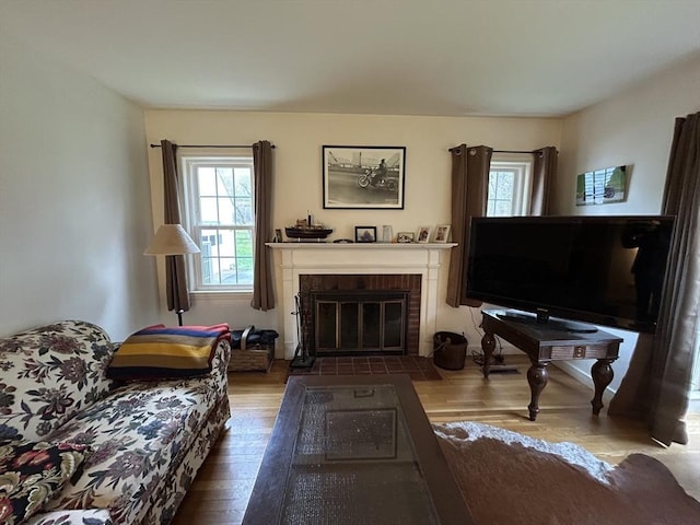 sitting room with a brick fireplace and wood finished floors