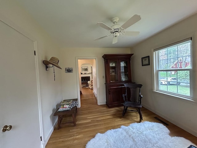 living area featuring baseboards, light wood finished floors, ceiling fan, and visible vents