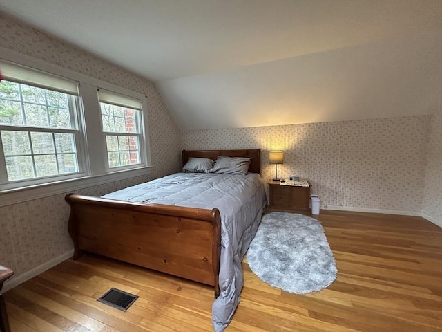 bedroom featuring wallpapered walls and wood finished floors