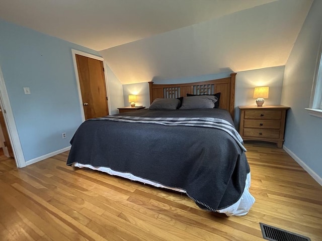 bedroom with light wood-type flooring, baseboards, lofted ceiling, and visible vents