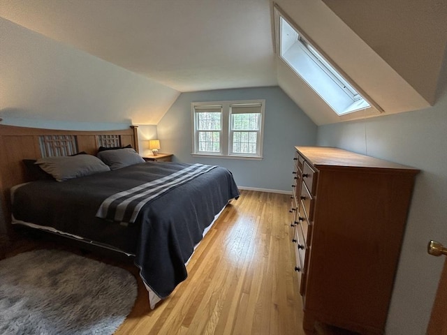 bedroom featuring light wood-style floors, baseboards, and lofted ceiling with skylight