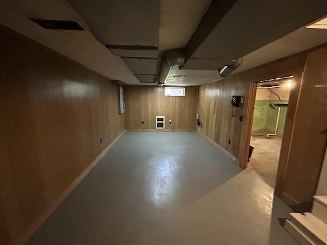 basement with heating unit and wood walls