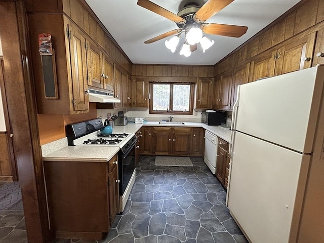 kitchen featuring a sink, white appliances, light countertops, stone finish flooring, and under cabinet range hood