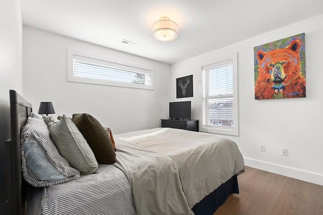 bedroom featuring wood finished floors, visible vents, and baseboards