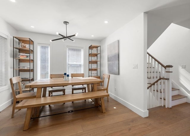 dining area featuring baseboards, recessed lighting, stairs, light wood-style floors, and a notable chandelier