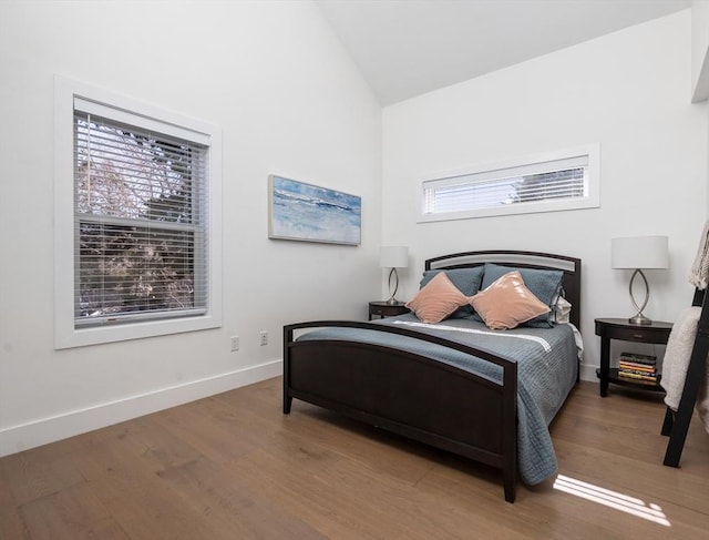 bedroom with vaulted ceiling, baseboards, and wood finished floors