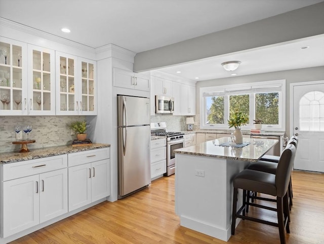 kitchen featuring light stone countertops, a center island, white cabinets, and stainless steel appliances