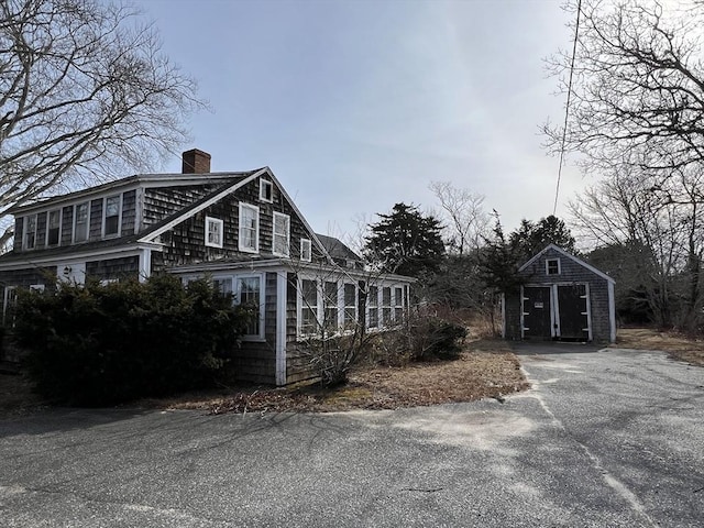 view of home's exterior with a chimney and an outdoor structure