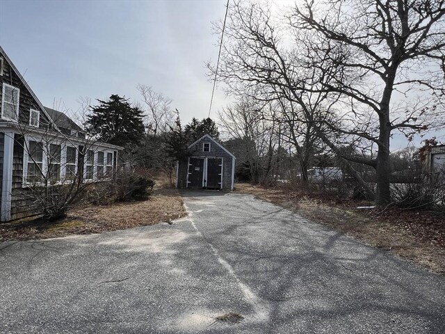 view of yard featuring an outbuilding, a shed, and asphalt driveway