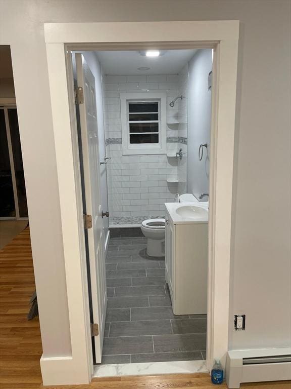 full bathroom with toilet, a stall shower, a baseboard heating unit, and wood finish floors