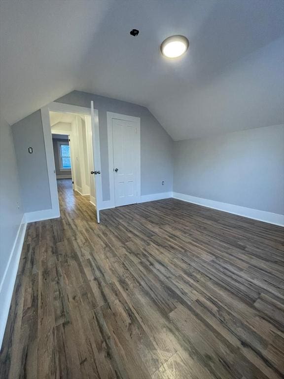 bonus room featuring lofted ceiling, dark wood-style flooring, and baseboards