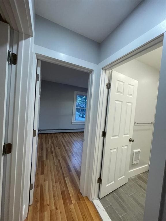 hallway featuring a baseboard radiator, visible vents, and wood finished floors