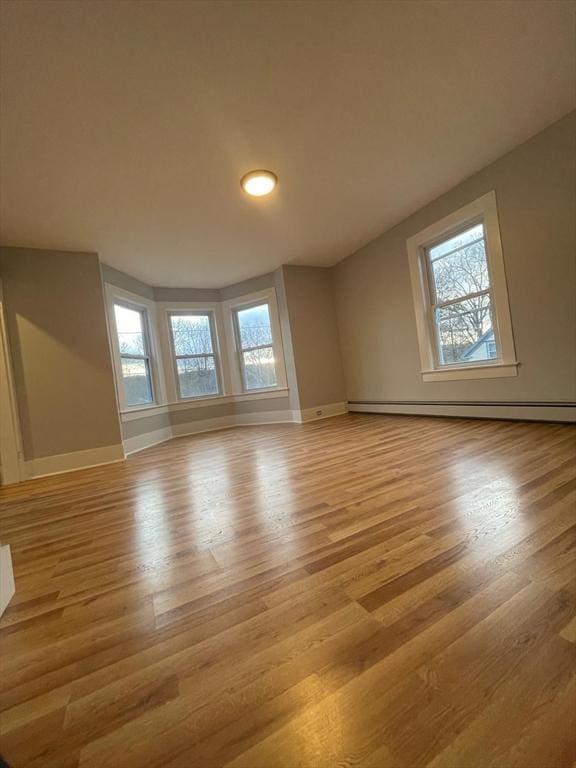 interior space featuring a baseboard heating unit, light wood-style flooring, and baseboards