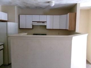 kitchen with light countertops, freestanding refrigerator, exhaust hood, and white cabinetry