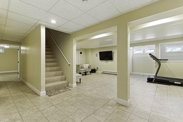 26 Waterville Ln, Shrewsbury, MA 01545 - below grade area with a baseboard heating unit, stairway, light tile patterned flooring, baseboards, and a drop ceiling