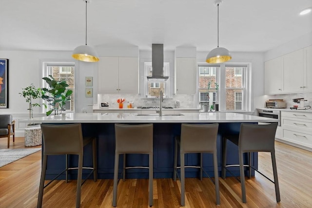 kitchen featuring backsplash, light countertops, a sink, and white cabinetry