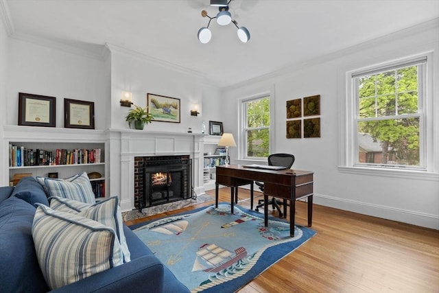 office with crown molding, wood finished floors, a fireplace with flush hearth, and baseboards