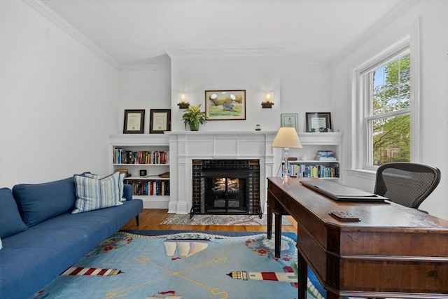 living area featuring wood finished floors, plenty of natural light, a tiled fireplace, ornamental molding, and an office area
