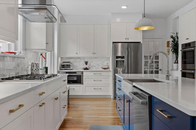 kitchen featuring blue cabinets, stainless steel appliances, a sink, white cabinetry, and light countertops