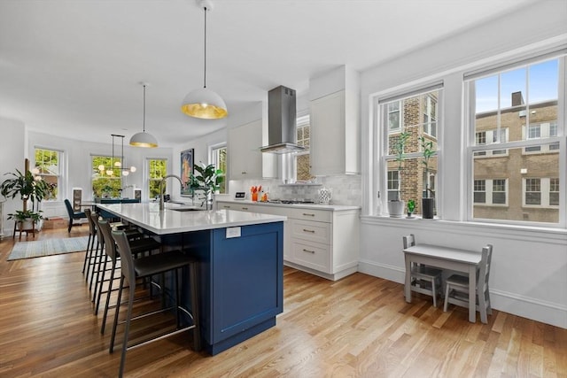 kitchen with island range hood, light countertops, a breakfast bar area, light wood-style flooring, and plenty of natural light