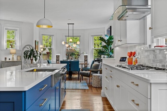 kitchen with blue cabinetry, stainless steel gas cooktop, light countertops, dark wood-type flooring, and white cabinets