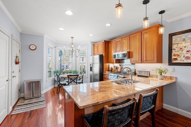 kitchen with appliances with stainless steel finishes, kitchen peninsula, sink, and hanging light fixtures