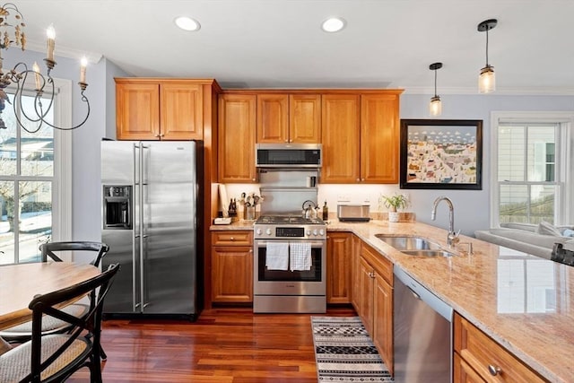 kitchen with sink, crown molding, stainless steel appliances, light stone counters, and decorative light fixtures