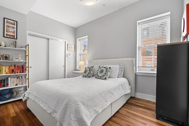 bedroom with a closet, baseboards, and wood finished floors