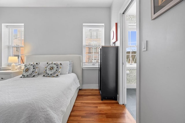 bedroom featuring multiple windows, wood finished floors, and baseboards