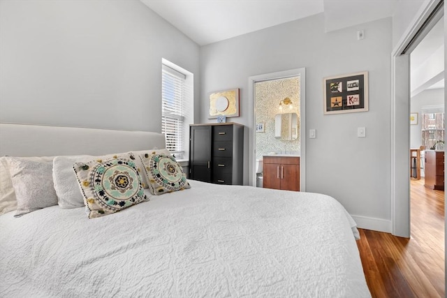 bedroom with multiple windows, wood finished floors, and baseboards