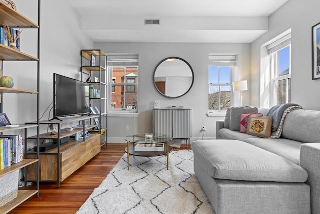 living area with radiator, wood finished floors, visible vents, and baseboards