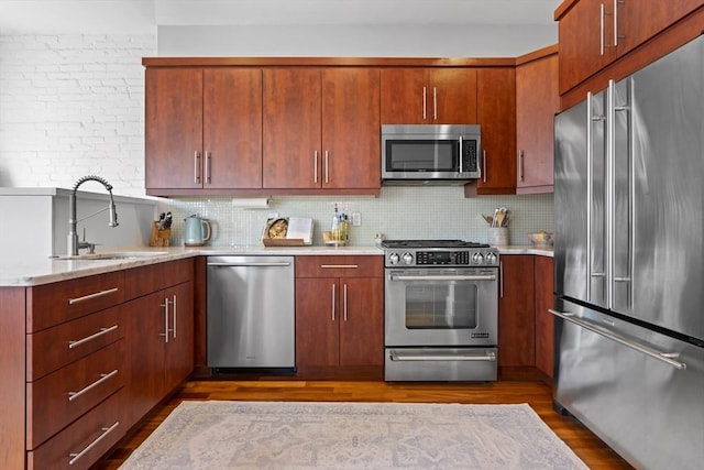 kitchen featuring stainless steel appliances, dark wood-type flooring, a sink, and decorative backsplash