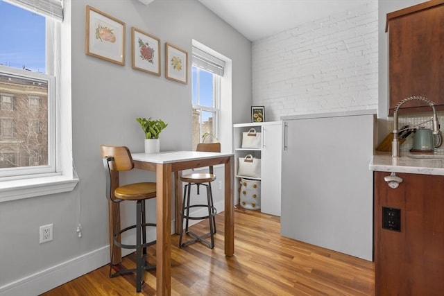 interior space featuring light wood-style floors, baseboards, and brick wall