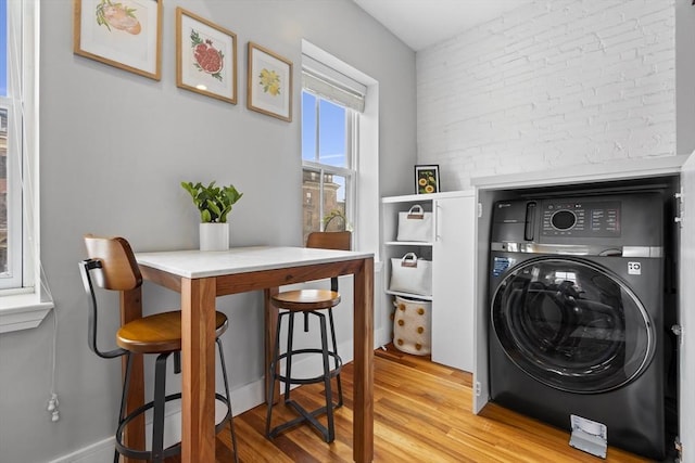 laundry room with washer / dryer, brick wall, laundry area, and light wood-style floors