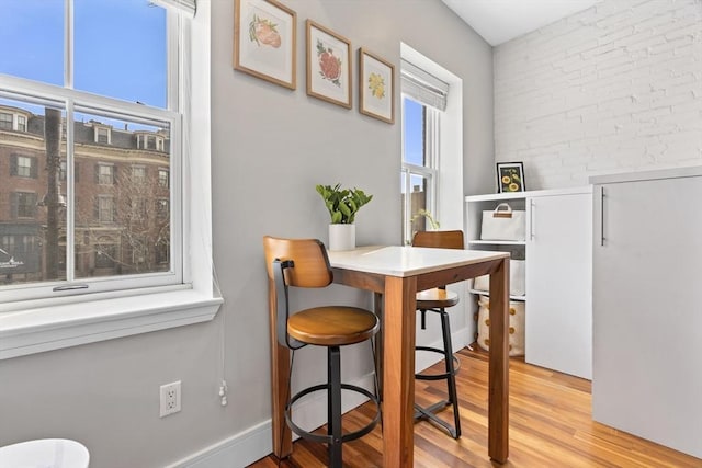 dining space with light wood finished floors and brick wall