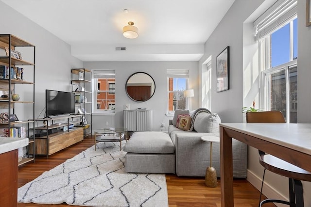 living room with wood finished floors, visible vents, and baseboards