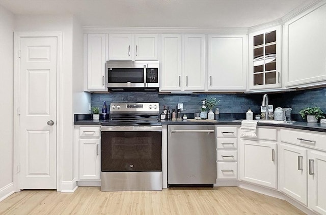 kitchen featuring appliances with stainless steel finishes, backsplash, sink, white cabinets, and light hardwood / wood-style floors