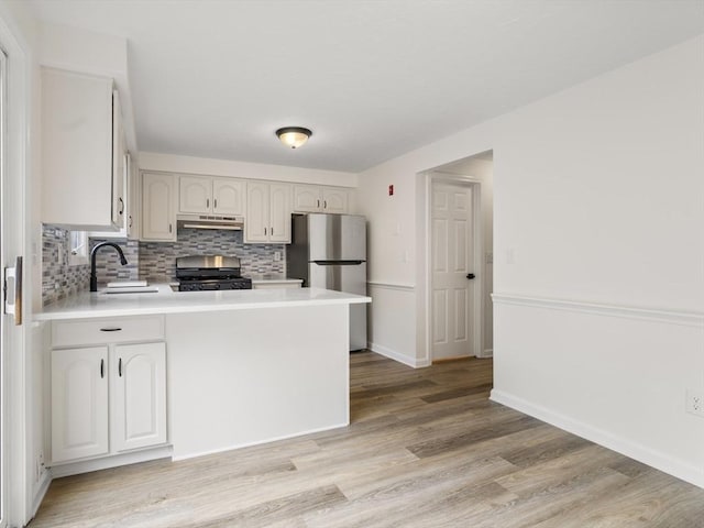 20 Washington St Unit 15, Easton, MA 02356 - kitchen featuring appliances with stainless steel finishes, a sink, a peninsula, decorative backsplash, and light wood-style floors