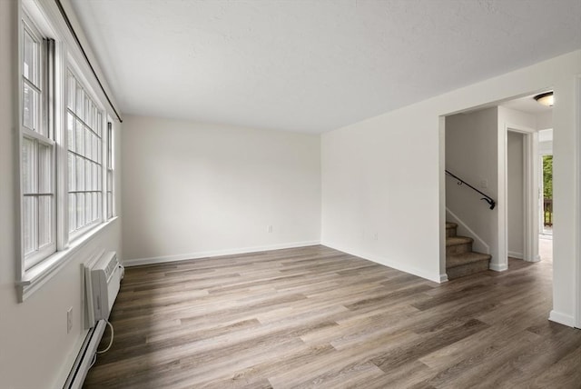 20 Washington St Unit 15, Easton, MA 02356 - spare room featuring stairs, wood finished floors, baseboards, a baseboard heating unit, and a wall mounted air conditioner
