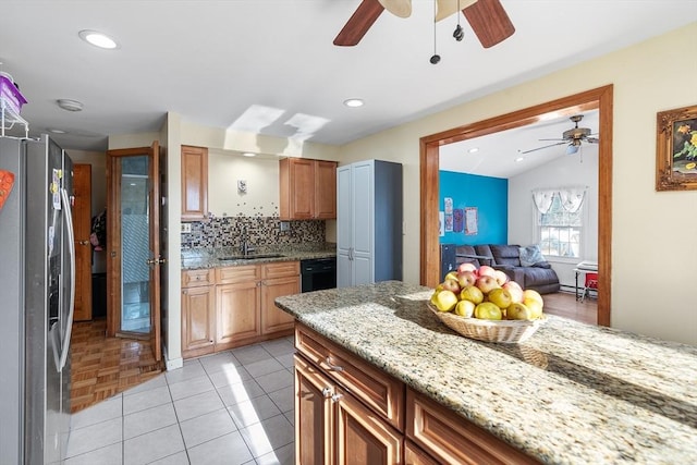 kitchen featuring sink, light stone counters, tasteful backsplash, stainless steel fridge, and dishwasher