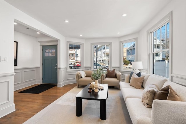 living room with a wainscoted wall, a decorative wall, wood finished floors, and recessed lighting