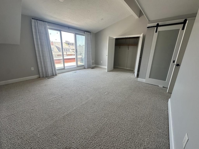 158 Quincy Shore Dr Unit 78, Quincy, MA 02171 - unfurnished bedroom featuring vaulted ceiling, access to outside, light colored carpet, a textured ceiling, and a barn door
