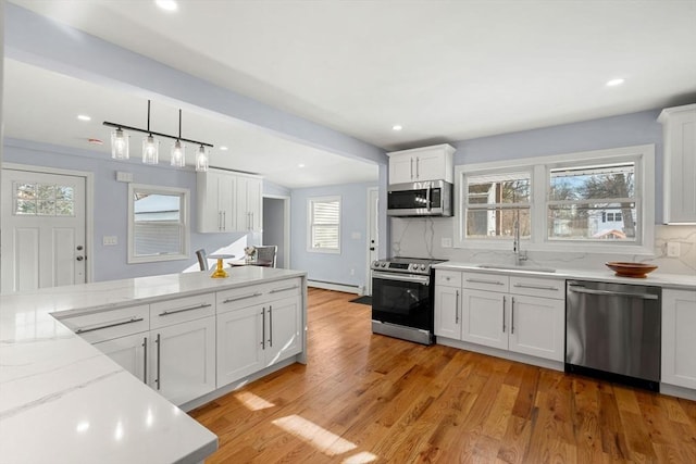 kitchen featuring stainless steel appliances, sink, decorative light fixtures, white cabinets, and tasteful backsplash