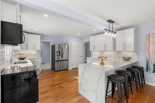 kitchen featuring tasteful backsplash, white cabinetry, stainless steel refrigerator with ice dispenser, and sink