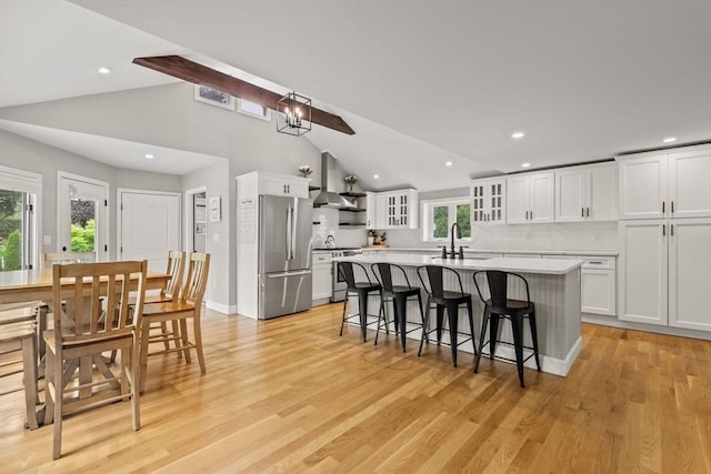 85 Mann Hill Rd, Scituate, MA 02066 - kitchen with appliances with stainless steel finishes, wall chimney range hood, an island with sink, a breakfast bar, and light countertops