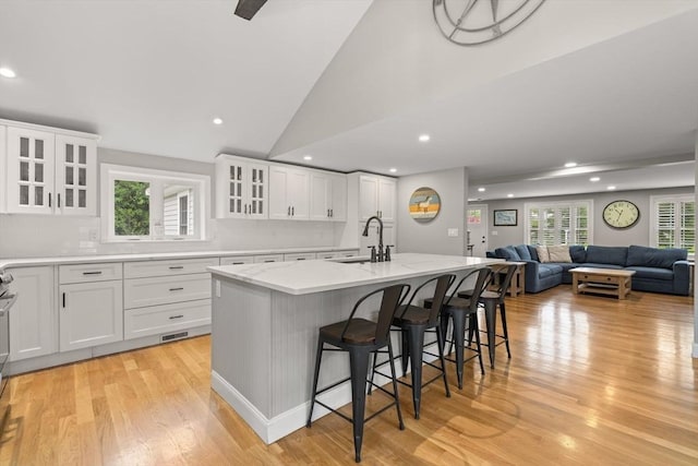 85 Mann Hill Rd, Scituate, MA 02066 - kitchen with light wood-type flooring, recessed lighting, a kitchen island with sink, a breakfast bar, and light stone countertops