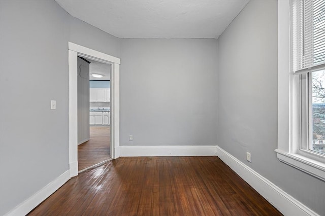 empty room with hardwood / wood-style floors and baseboards