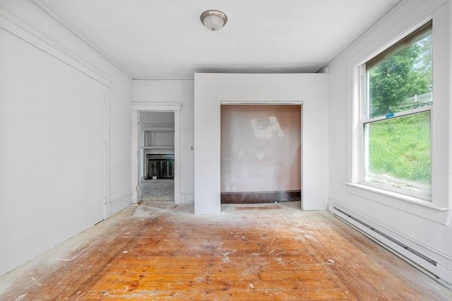 spare room with baseboard heating, plenty of natural light, and a glass covered fireplace